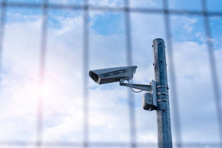 Street security camera next to iron fence, border, prison, concept pictureの写真素材
