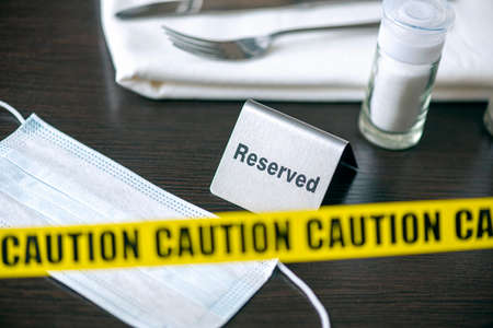 Caution - yellow tape over table in cafe or restaurant and sign reserved. Social distancingの写真素材
