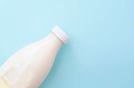 Plastic bottle with milk on blue surface, lay out, top view