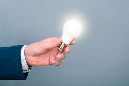A man holding glowing light bulb in a hand. Concept picture about new idea, inspiration, business