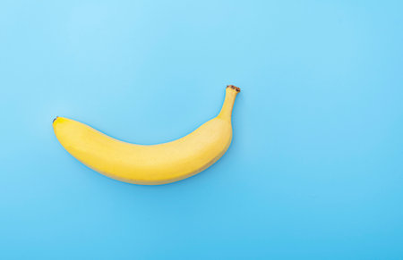 Creative picture of ripe fresh yellow banana on blue surface, table, backgroundの写真素材
