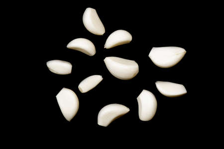 Some cloves of raw peeled garlic isolated on black backgroundの写真素材