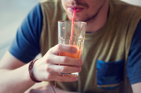 Male drinking the carrot juice at a kitchen or a cafeの写真素材