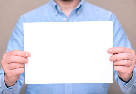 A man in blue shirt, businessman holding white blank sheet. Space for text, mockupの写真素材