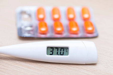 Close-up Thermometer showing high Temperature 37 and Pills on Tableの写真素材