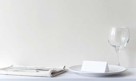 Blank invitation card on white plate in restaurant. Interior of restaurant with table, cutlery before celebrate, mockup, space for textの写真素材