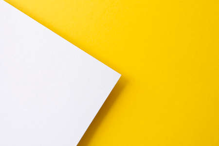 Yellow and white colored paper with shadows as background, top view, space for text, flat layの写真素材