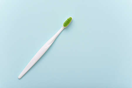 White plastic toothbrush with green bristle as flat lay. Toothbrush on blue surface, top view, space for text.の写真素材