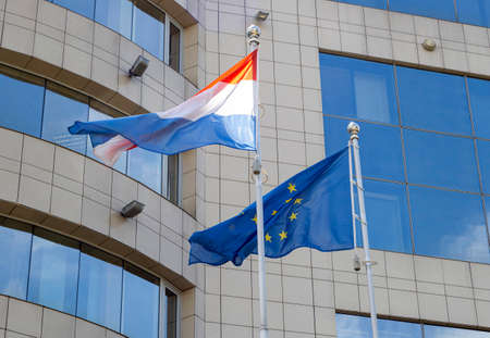 Flags of the Netherlands and European Union on flagpole waving during windy day. Netherlands and EU flags on the flagpole.の写真素材