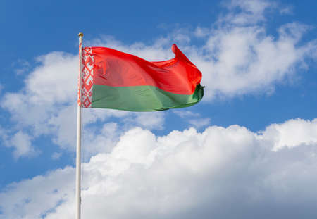 Flag of Belarus on flagpole waving against blue sky