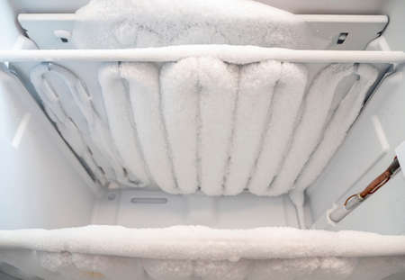Close-up of opened deep freezer with ice and snow. Freezer before defrost. Empty shelves of fridge.の写真素材