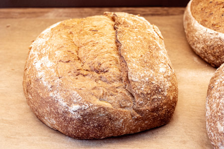Close-up of loaf of brown homemade bread, brown dark bread with grains on the shop shelfの写真素材