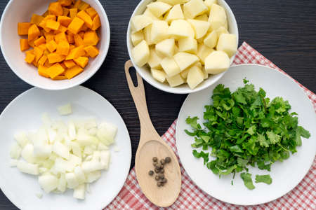 Ingredients for soup, top view of carrot, onion, potato, cilantro, pepper in ceramic white plates, vegetable setの写真素材