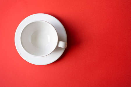 Simple flat lay composition with empty white ceramic cup, mug, bowl on a plate with bright red background, top view, space for textの写真素材