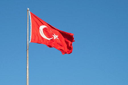 Turkish flag or flag of Turkey waving on flagpole against blue sky in Istanbul. Space for text.の写真素材