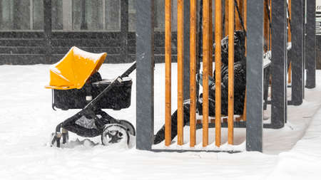 Parent with baby stroller and newborn walking at the city park during winter snowfallの写真素材