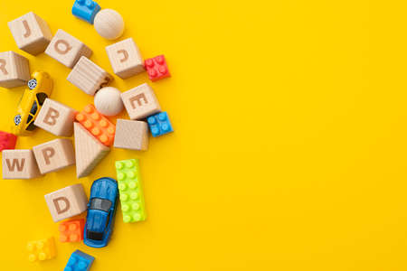 Wooden cubes, plastic constructor and cars toy on bright yellow background, concept flat lay about child educationの写真素材