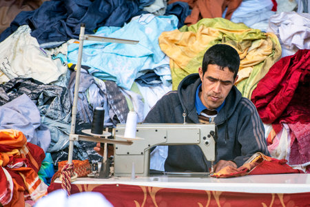 ESSAOUIRA - JAN 03: Man worker sewing clothes at an oriental street market in Medina district in Essaouira, January 03. 2018 in Moroccoのeditorial素材