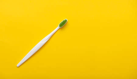 White plastic toothbrush on bright yellow background as flat lay, top view, space for textの写真素材