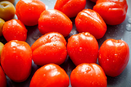 Group of wet ripe Cherry tomatoes with drops on a black plate, top viewの写真素材