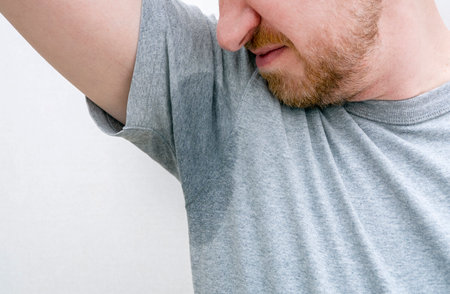 Person sniffing armpit. Sweaty armpit, wet underarm, stained sweat on gray t-shirt