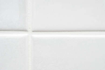 Close-up of part of white ceramic tile on the wall with clean new seam and puttyの写真素材