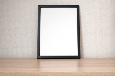 Black photo frame with blank white space on wooden shelf, desk. Mockup, template space for textの写真素材