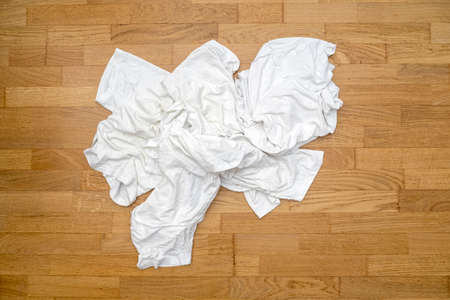 Messy dirty white sport t-shirts on wooden floor before washing in laundryの写真素材
