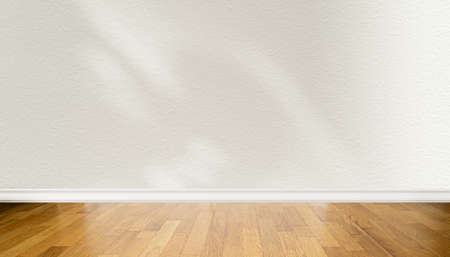 Front view of wooden parquet floor and blank light beige wall with abstract shadowsの写真素材