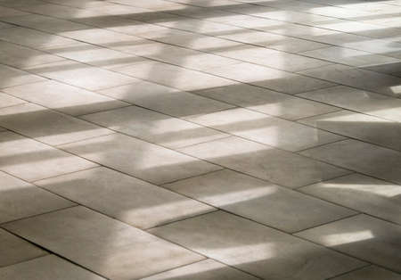 Abstract shadows, silhouettes, lines on the tiled floor through a window during sunny dayの写真素材