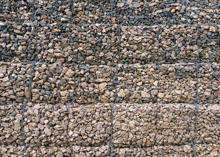 Gabion with heaps of small stones in a grid as the city or garden decoration, textured backgroundの写真素材
