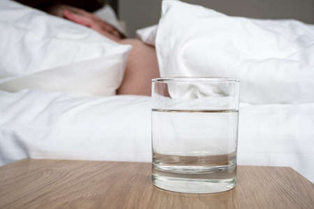Glass with water in front of bed in the morningの写真素材