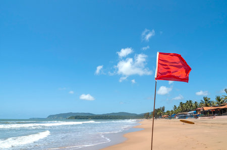 Red flag as warning sign on the beach before storm means no swimming, during windy sunny dayの写真素材