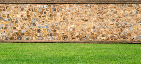 Panoramic view of the old vintage stone wall and green lawn at a garden as landscape designの写真素材