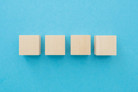 Four wooden cubes, square shape with blank surface on blue background, for business concept ideasの写真素材