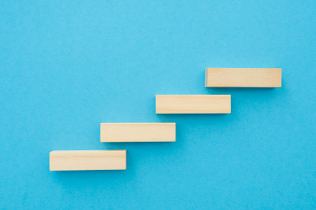 Four wooden small planks, long shape with blank surface growing up on blue background, for business concept ideasの写真素材