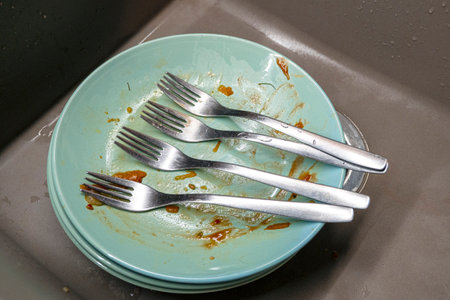Dirty plates with four forks in a kitchen sink, top viewの写真素材