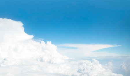 Panoramic view of blue sky and cumulus clouds through an airplane window. Flight above white cloud and horizon.の写真素材