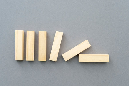Row of falling vertical wooden shapes business concept picture about team building, leadership, supporting. Blank wooden figures on gray background.の写真素材