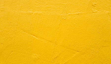 Rough blank wall painted by bright yellow paint as texture background or backdropの写真素材