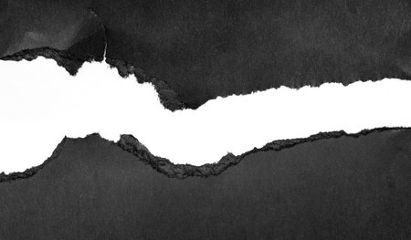 Piece of torn black paper, cardboard with hole, gap isolated on whiteの写真素材