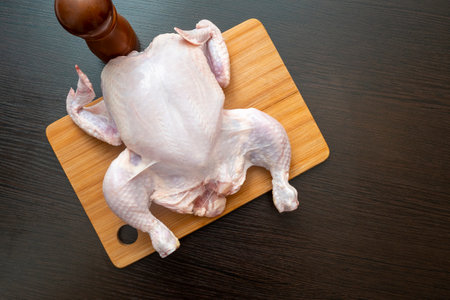 Raw chicken carcass on wooden table at a kitchen, top viewの写真素材