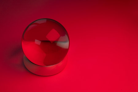 Glass crystal ball on a table with red lightの写真素材
