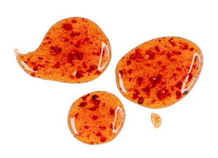 Drops of sour sweet sauce with pieces of chilli pepper isolated on white, top viewの写真素材