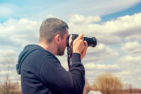 Person taking picture by reflex camera. Man with black photo camera in warm summer dayの写真素材
