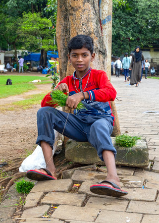 MUMBAI - SEPT 21: Indian boy sitting on the ground at public city park in Mumbai on September 21. 2022 in Indiaのeditorial素材