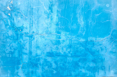 Wall with bright light blue paint on surface, damaged cracked surface as texture or backgroundの写真素材