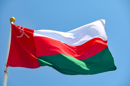 Flag of Oman on flagpole waving against blue skyの写真素材