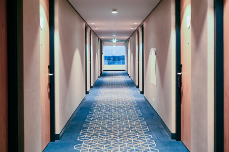 Long hallway with blue carpet and window in hotelの写真素材