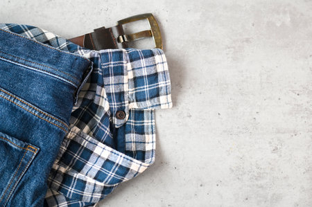 Messy casual things jeans, shirt and belt on a table, top view, space for text